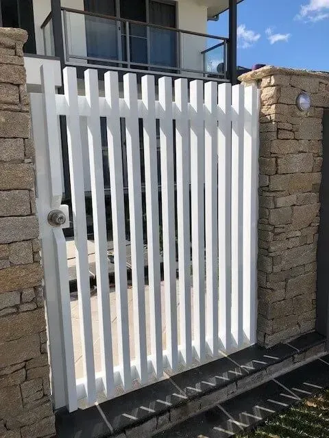A white gate is between two brick walls in front of a house. — Sunshine Gates in Kunda Park, QLD