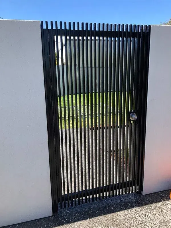 A black gate is sitting next to a white wall. — Sunshine Gates in Kunda Park, QLD