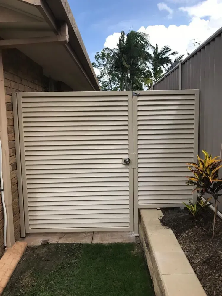 A Black Gate is Sitting Next to a White Wall — Sunshine Gates in Kunda Park, QLD