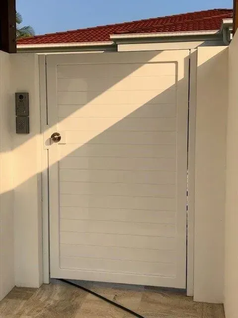 A Black Gate is Sitting Next to a White Wall — Sunshine Gates in Kunda Park, QLD