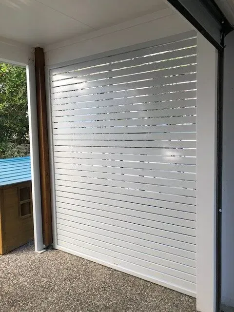 A white garage door with a blue roof is sitting on a porch. — Sunshine Gates in Kunda Park, QLD