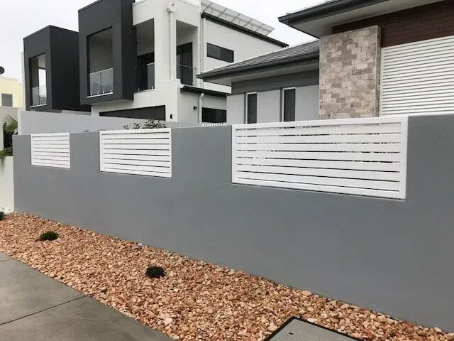 A gray wall with a white fence in front of a house. — Sunshine Gates in Kunda Park, QLD