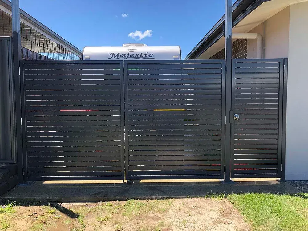 A black fence with a white trailer in the background. — Sunshine Gates in Kunda Park, QLD