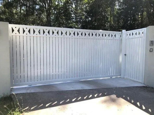 A white gate is open to a driveway with trees in the background. — Sunshine Gates in Kunda Park, QLD
