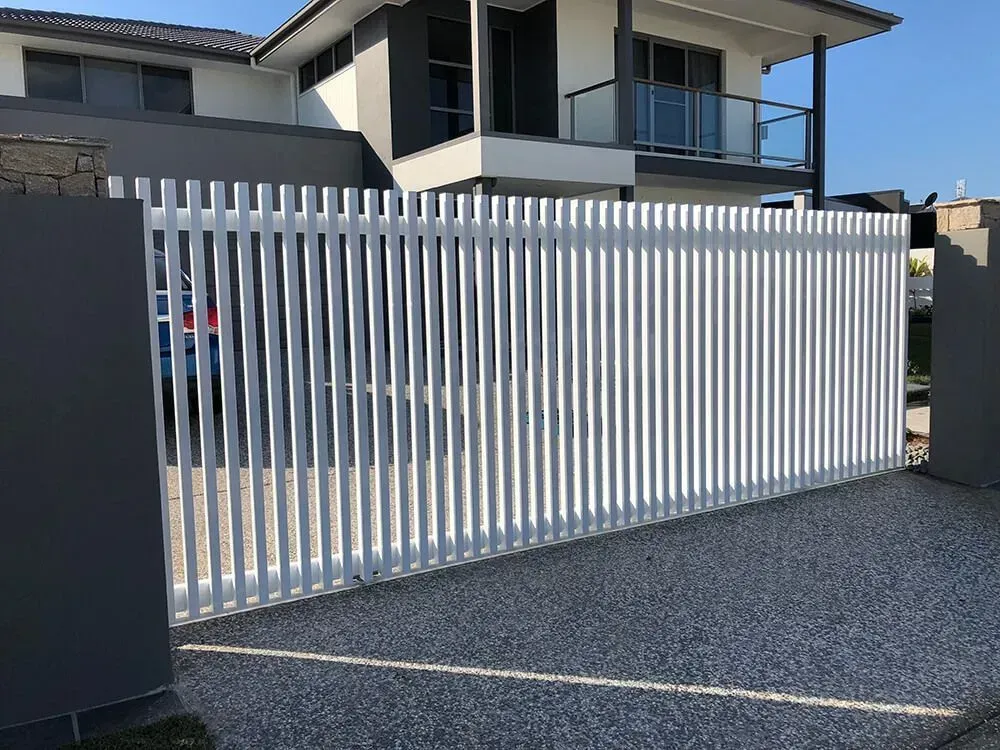 A white fence is in front of a large house. — Sunshine Gates in Kunda Park, QLD