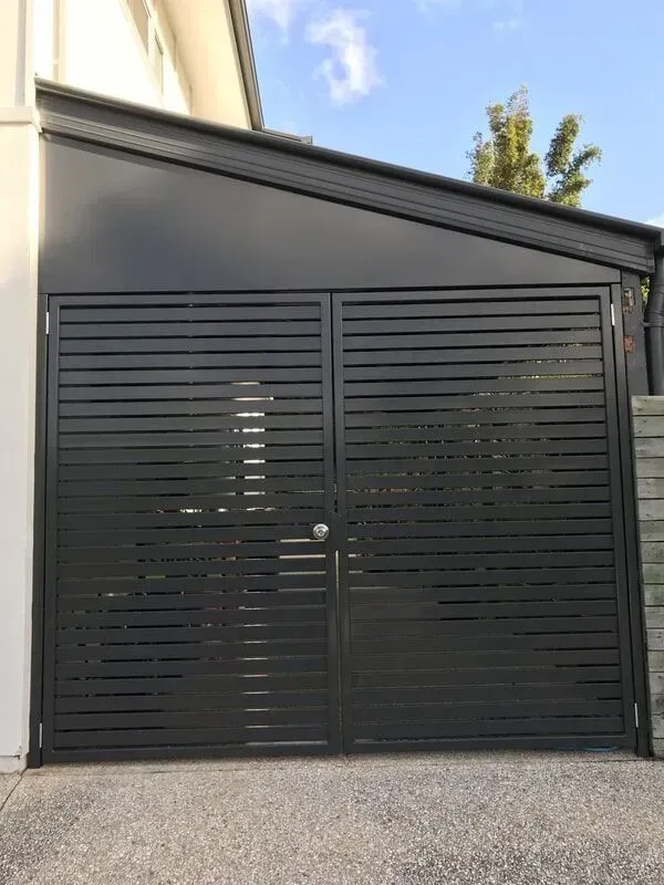 A black garage door is sitting next to a white house. — Sunshine Gates in Kunda Park, QLD