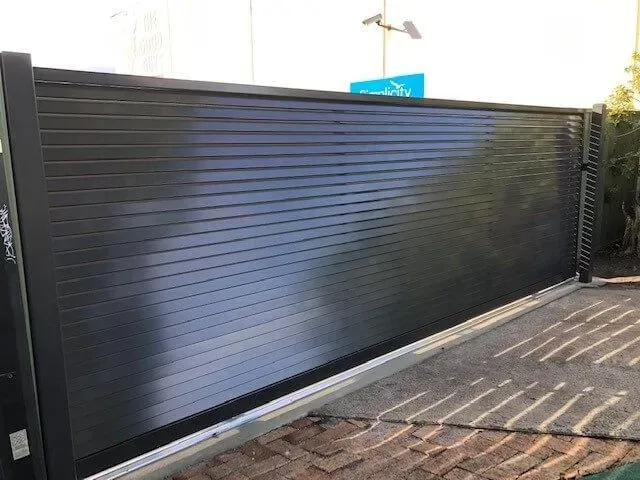 A black fence is sitting on top of a brick driveway. — Sunshine Gates in Kunda Park, QLD