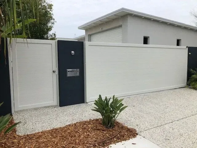 A white fence with a black gate in front of a house. — Sunshine Gates in Kunda Park, QLD