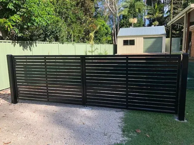 A black fence is sitting in front of a house. — Sunshine Gates in Kunda Park, QLD