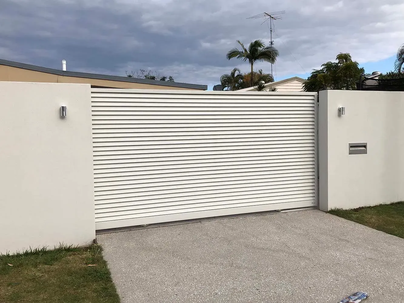 A white fence with a sliding gate in front of a house. — Sunshine Gates in Kunda Park, QLD