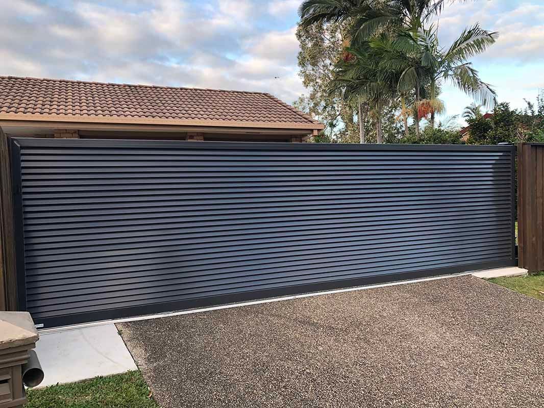 A black sliding gate is sitting in front of a house. — Sunshine Gates in Kunda Park, QLD