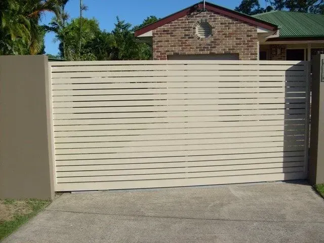 A white sliding gate is open in front of a house. — Sunshine Gates in Kunda Park, QLD
