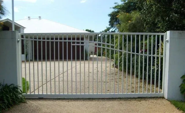 A white gate is open to a driveway in front of a house. — Sunshine Gates in Kunda Park, QLD