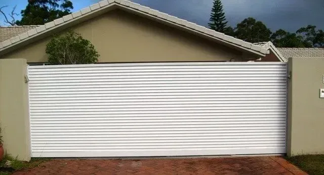 A white garage door is sitting in front of a house.