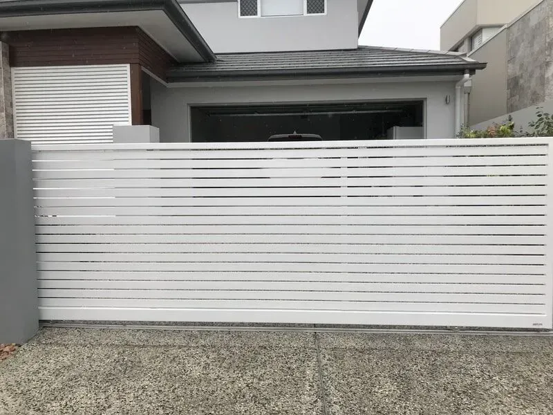 A white sliding gate is sitting in front of a house. — Sunshine Gates in Kunda Park, QLD