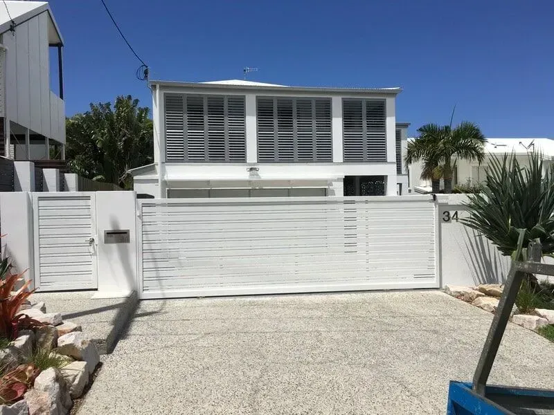 A white house with a sliding gate in front of it. — Sunshine Gates in Kunda Park, QLD