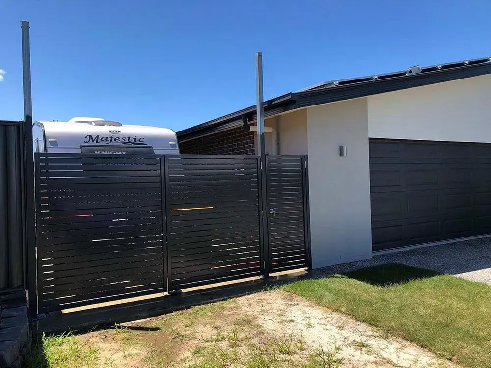 A caravan is parked in front of a house next to a fence. — Sunshine Gates in Kunda Park, QLD