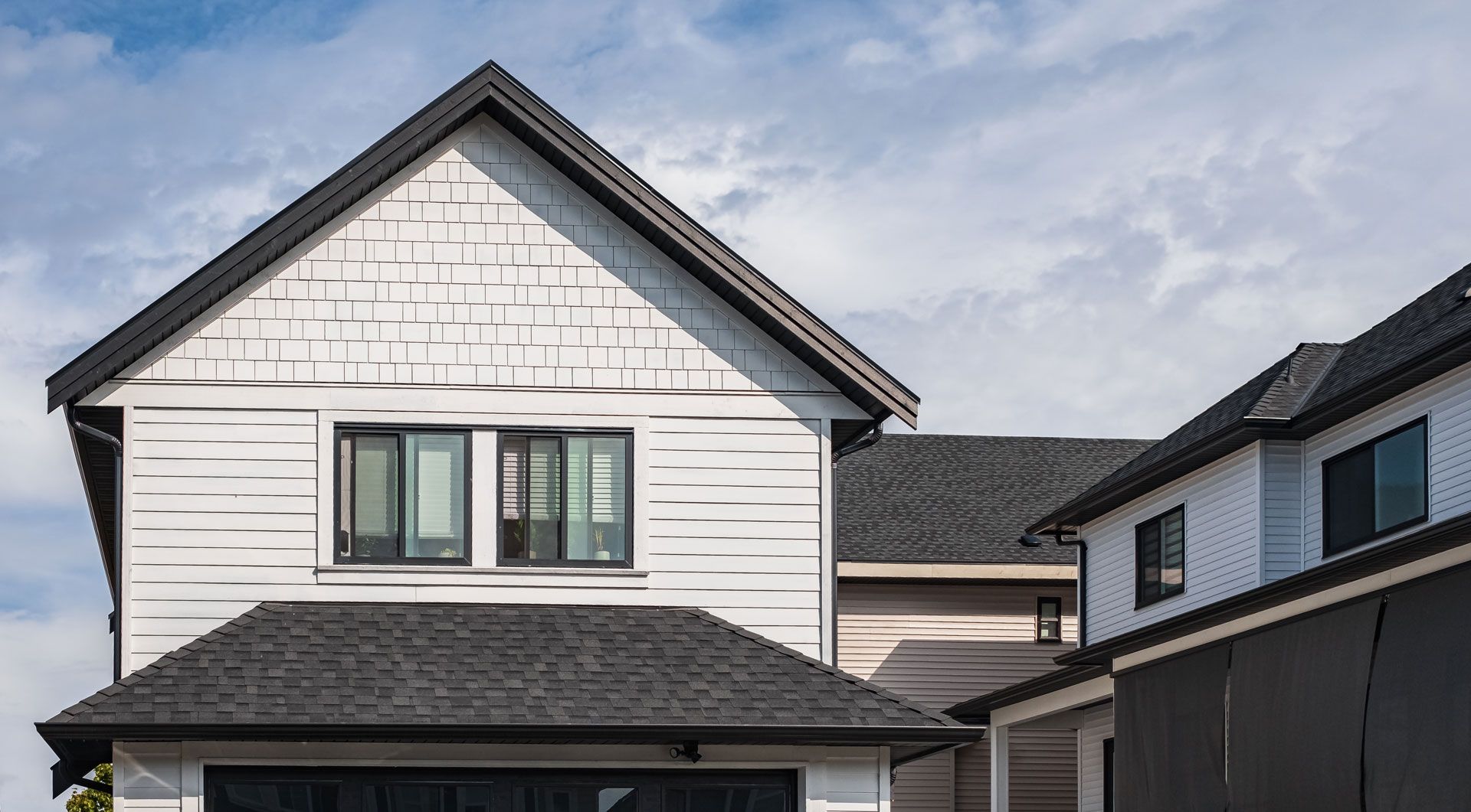 A white house with a black roof and a garage.