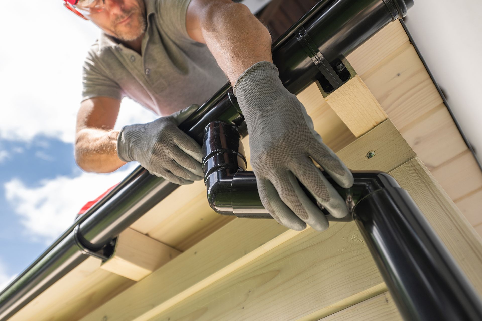 A man is installing a gutter on the roof of a house.
