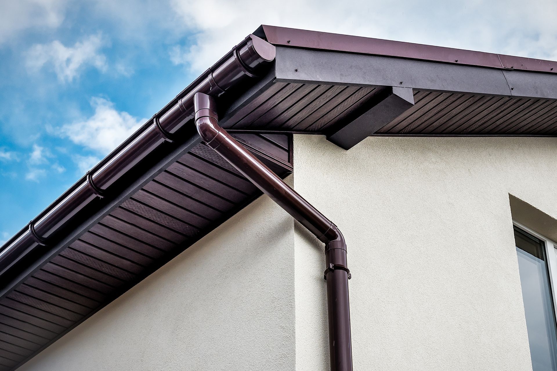 A house with a brown gutter on the side of it.