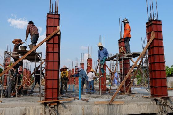 Construction workers building concrete pillars on a construction site.