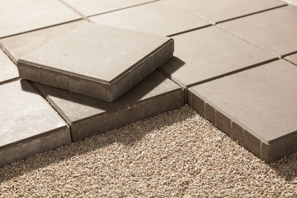 Paving stones being laid on a bed of gravel; close-up shows stone edges and arrangement.