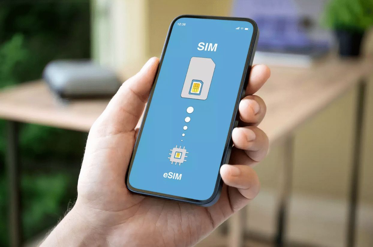 A person is holding a cell phone with a sim card on the screen.