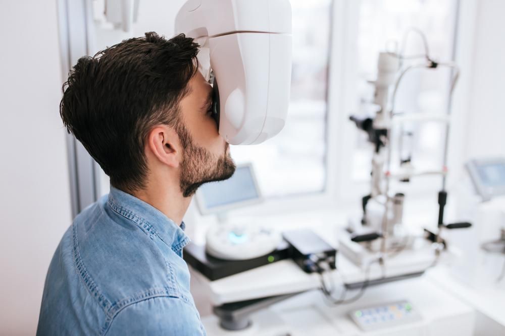 A Man Is Getting His Eyes Checked By An Ophthalmologist — Eyedentity Optical In Earlville, QLD