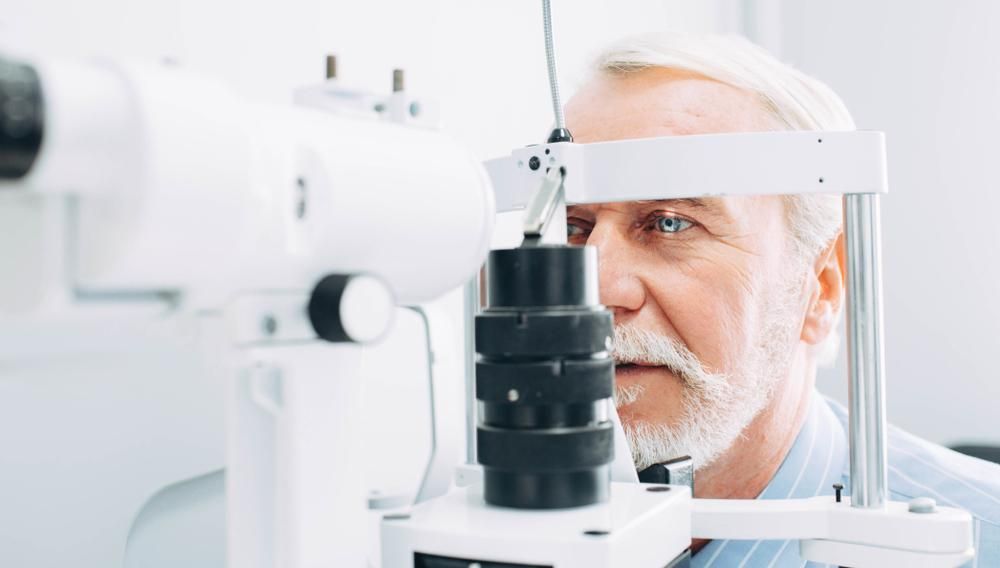 An Older Man Is Getting His Eyes Examined By An Ophthalmologist — Eyedentity Optical In Earlville, QLD