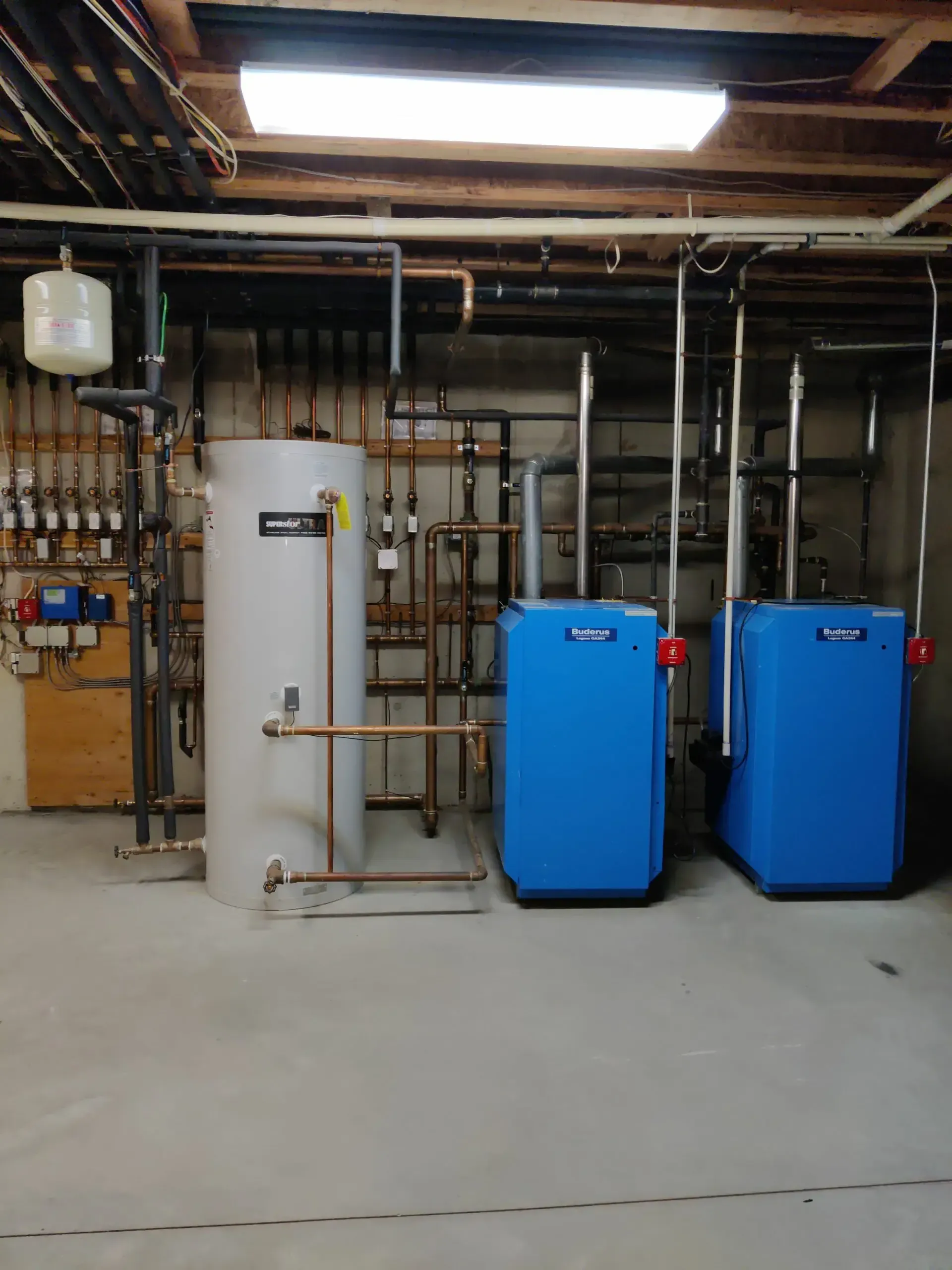 A room with two blue boilers and a white tank