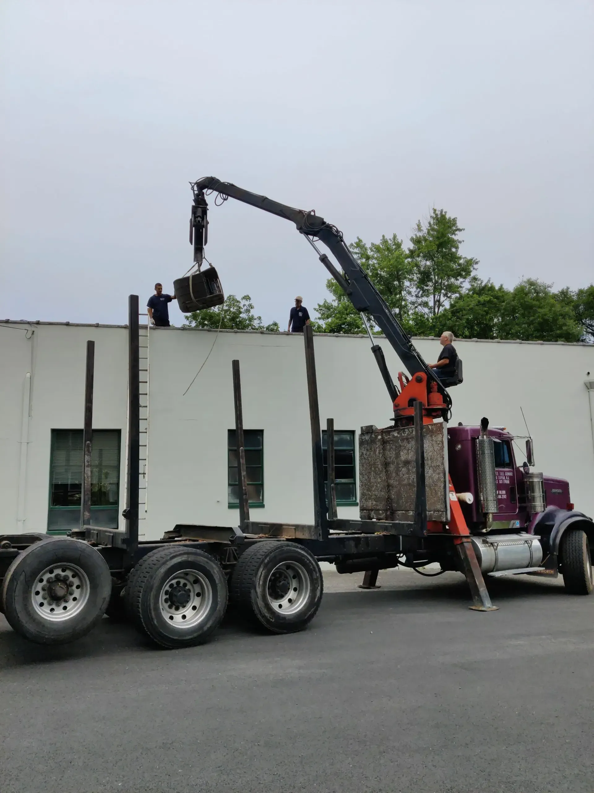 A truck with a crane attached to it is parked in front of a building