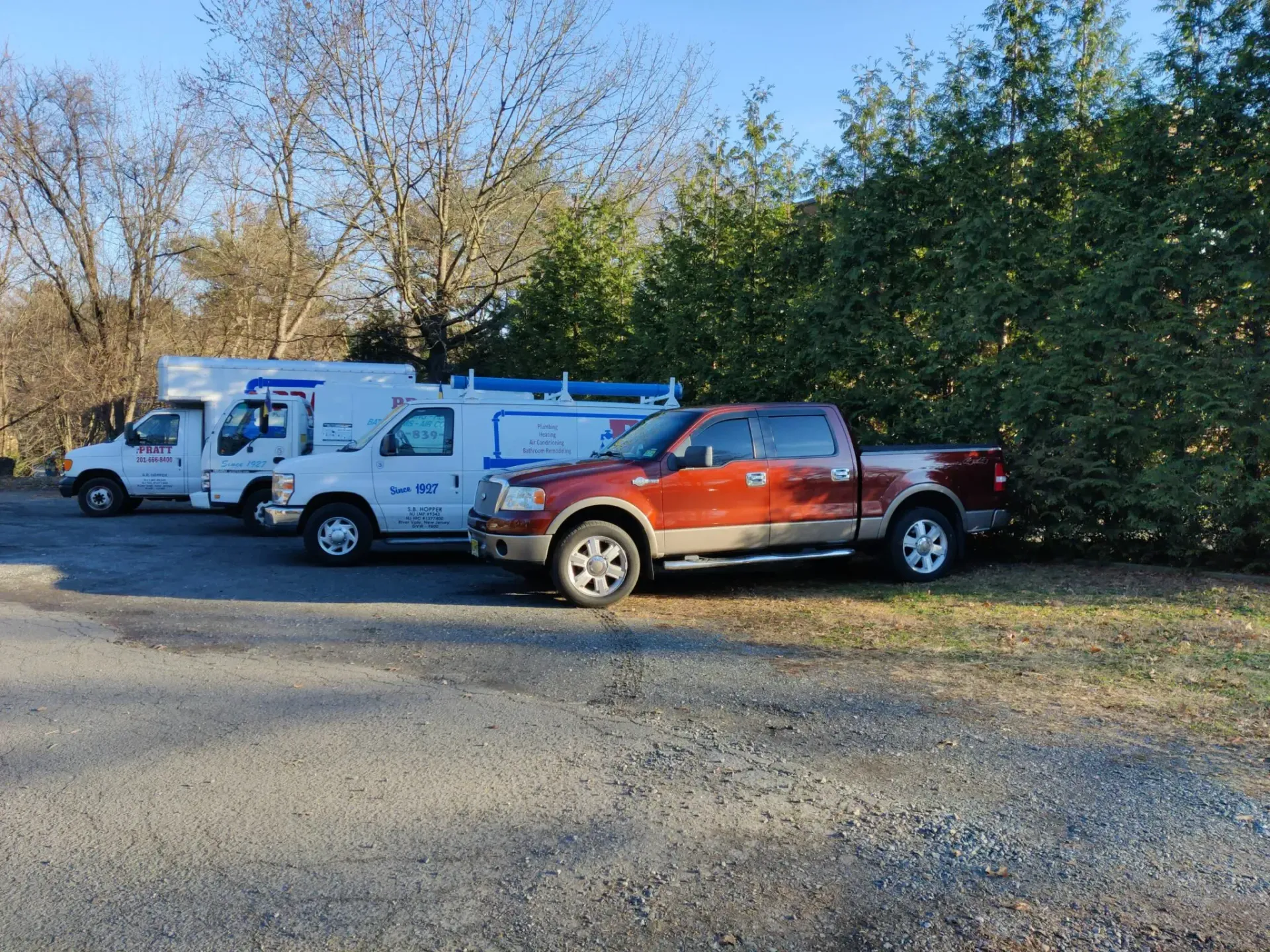 A red truck is parked next to a white truck in a parking lot.