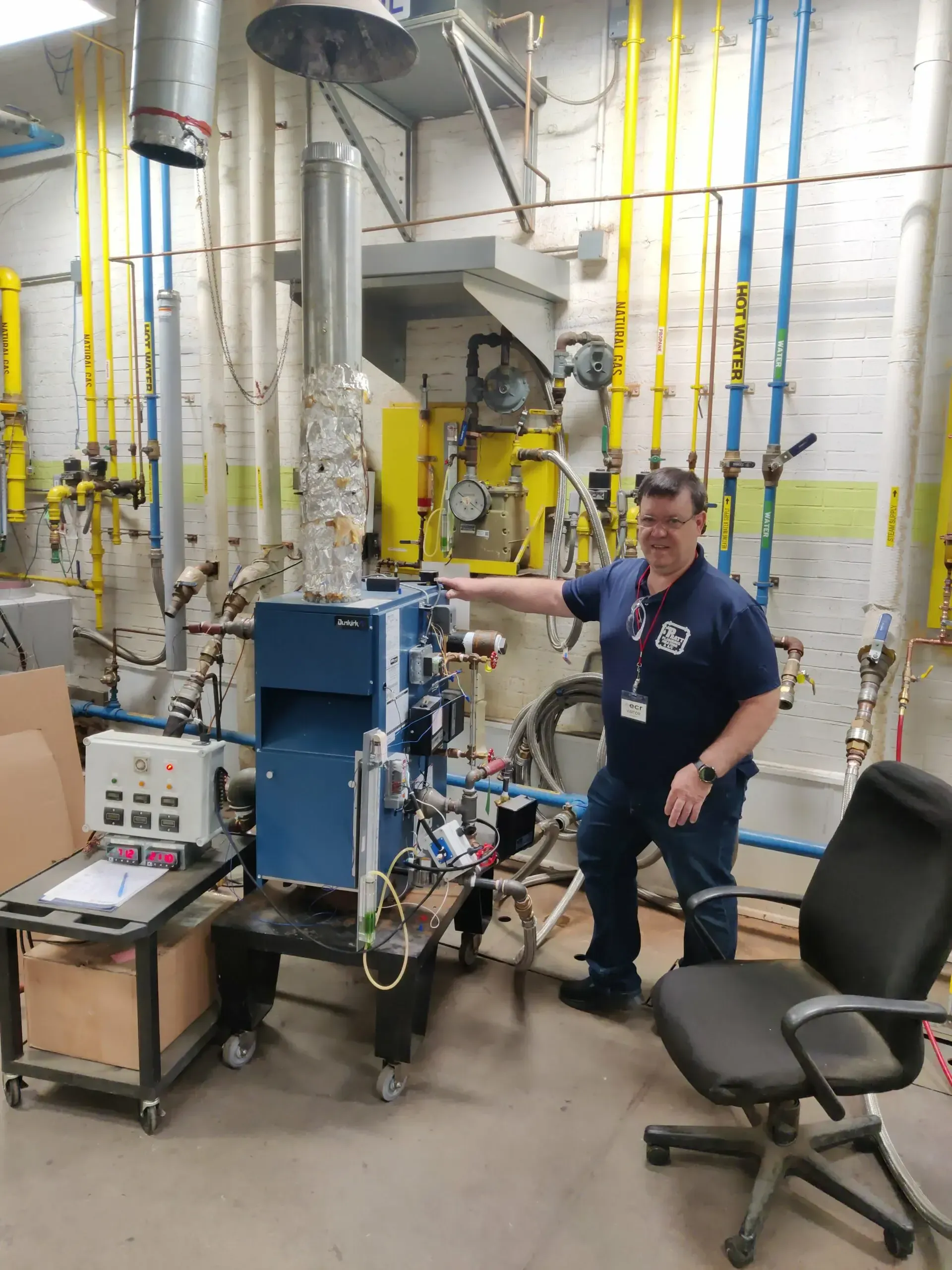 A man in a blue shirt is standing in front of a machine
