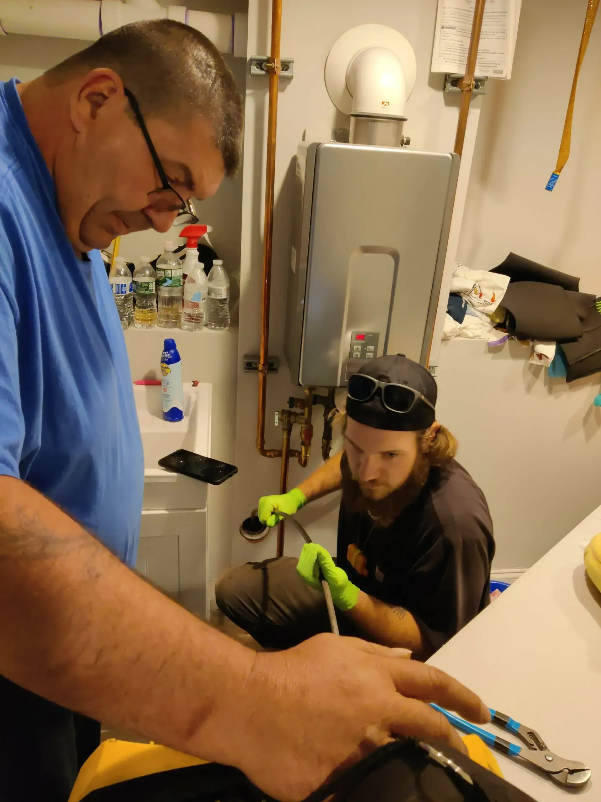 Two men are working on a boiler in a laundry room