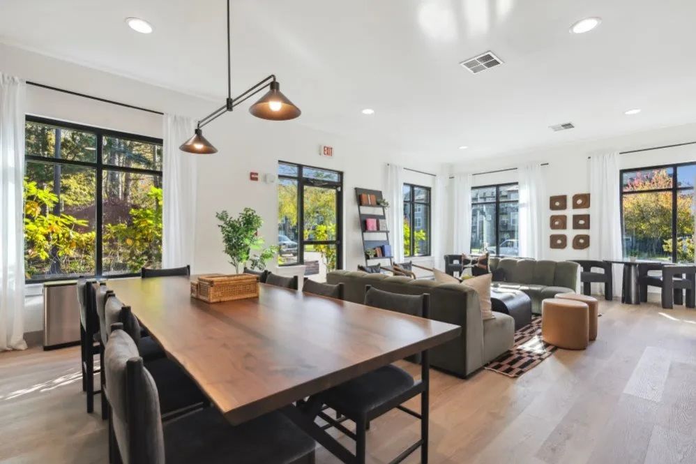 Large room with dining table, sofas, windows, and pendant lights at The Avery at Orenco Station, offers apartments for rent in Hillsboro, OR. Natural light illuminates interior.