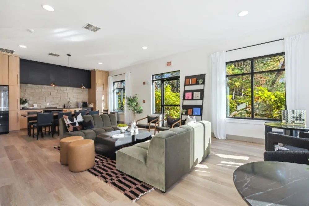 Modern living room with seating, dining area, and large windows with a view at The Avery at Orenco Station, offers apartments for rent in Hillsboro, OR.