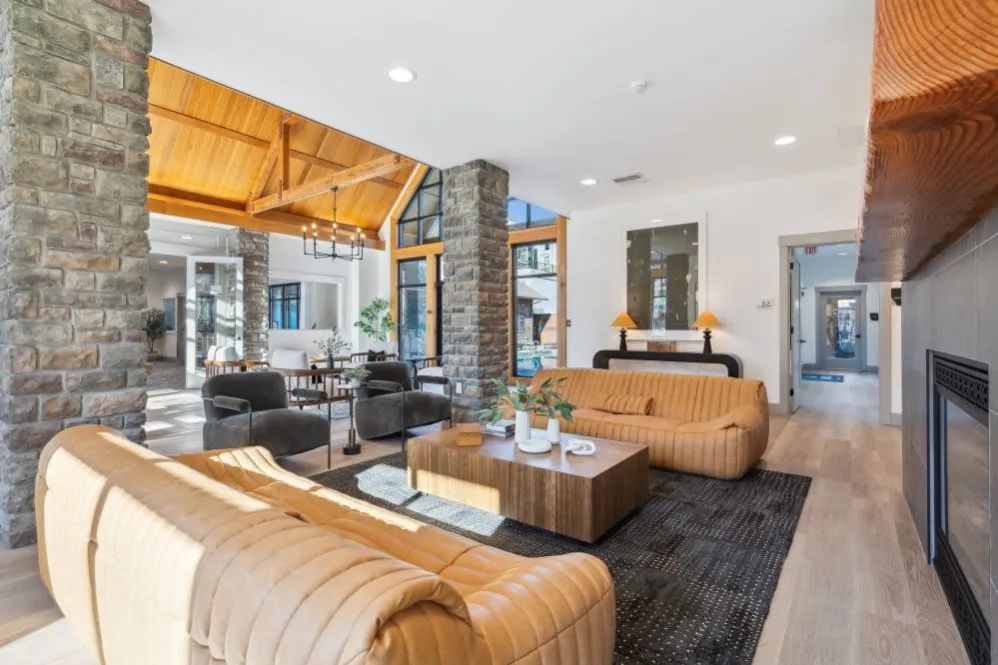 Spacious clubhouse with stone pillars, wood ceiling, leather sofas, and a rug at The Avery at Orenco Station, offers apartments for rent in Hillsboro, OR.