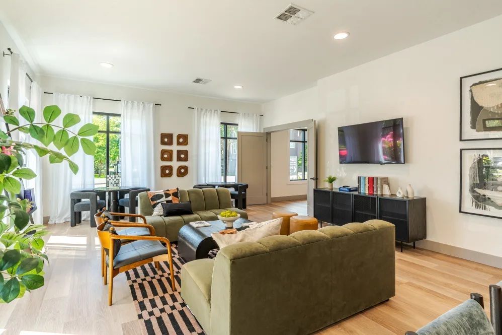 Living room with green sofas, wooden floors, and a TV on the wall at The Avery at Orenco Station, offers apartments near Orenco Station Town Center.