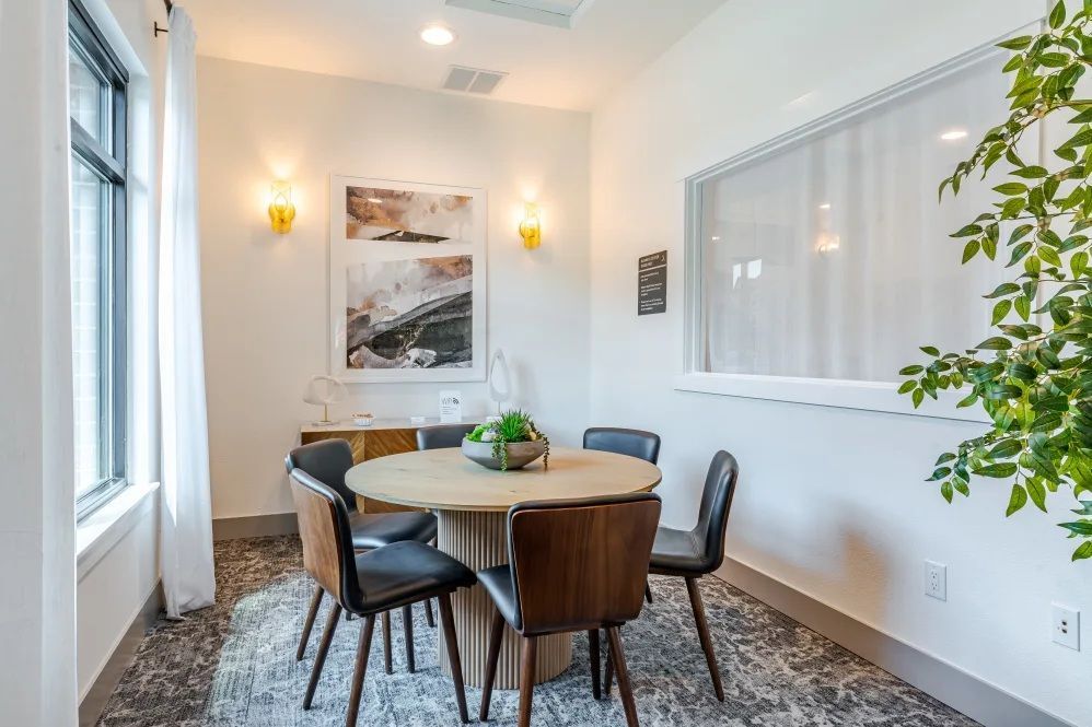 Dining area with round table, four chairs, artwork, and window with curtains at The Avery at Orenco Station, offers apartments near Orenco Station Town Center.