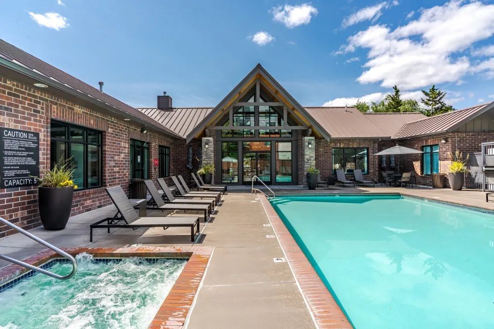 Pool area with lounge chairs, a hot tub, and a building with a peaked roof against a blue skyat The Avery at Orenco Station, offers apartments near Orenco Station Town Center.