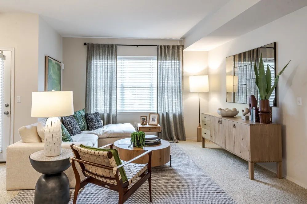 Living room with cream-colored sectional sofa, wooden cabinet, and neutral decor at The Avery at Orenco Station, offers apartments in Hillsboro, OR. 