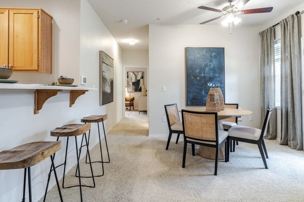 Open-concept dining and kitchen with a round table, bar stools, and hallway leading to another room at The Avery at Orenco Station, offers apartments in Hillsboro, OR. 