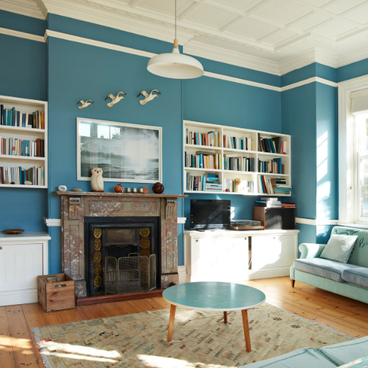 Blue living room with books, fireplace, and a small couch.