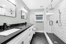 A bathroom with two sinks and a walk in shower.