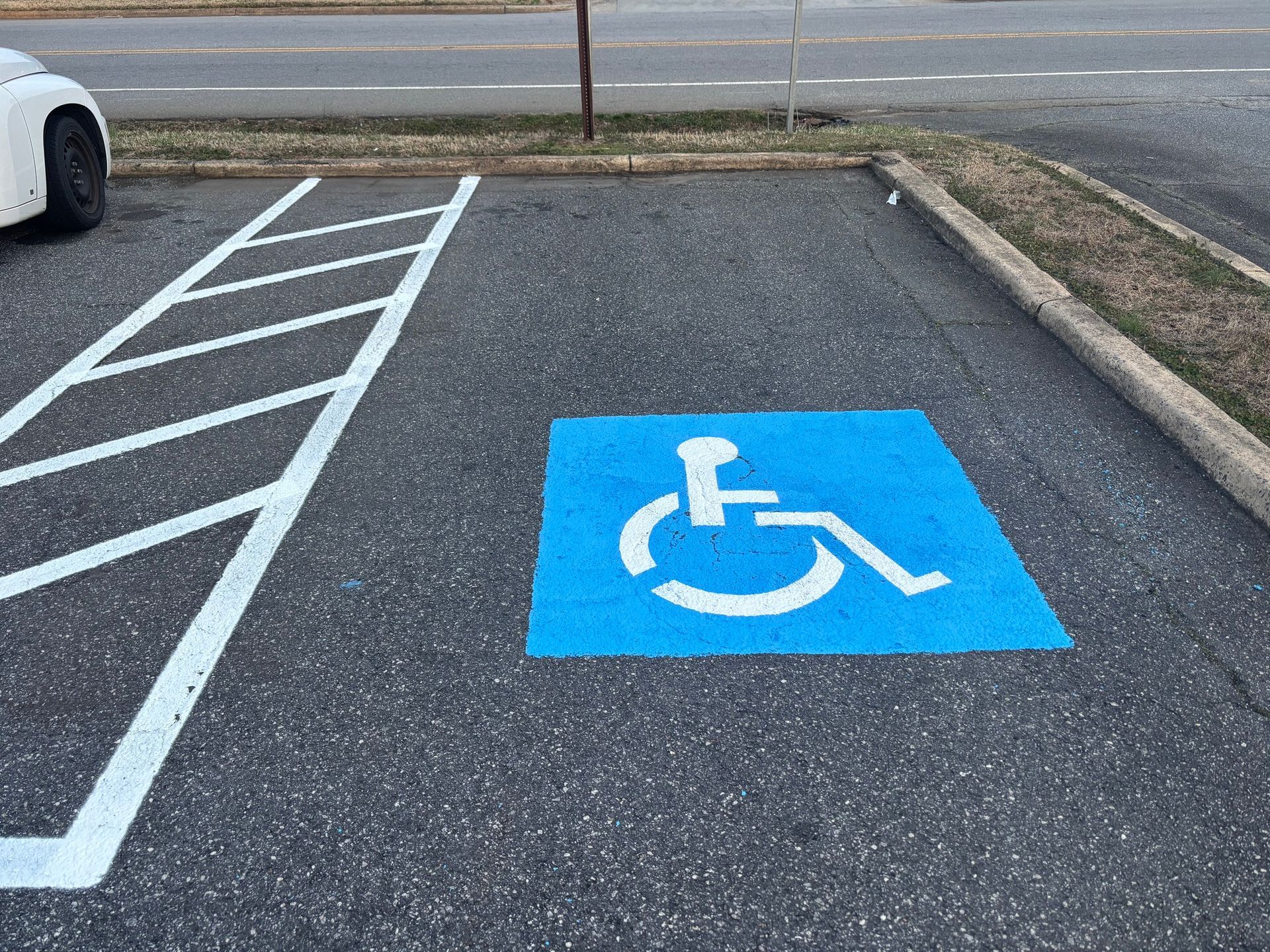 Blue and white handicap parking space in asphalt parking lot.