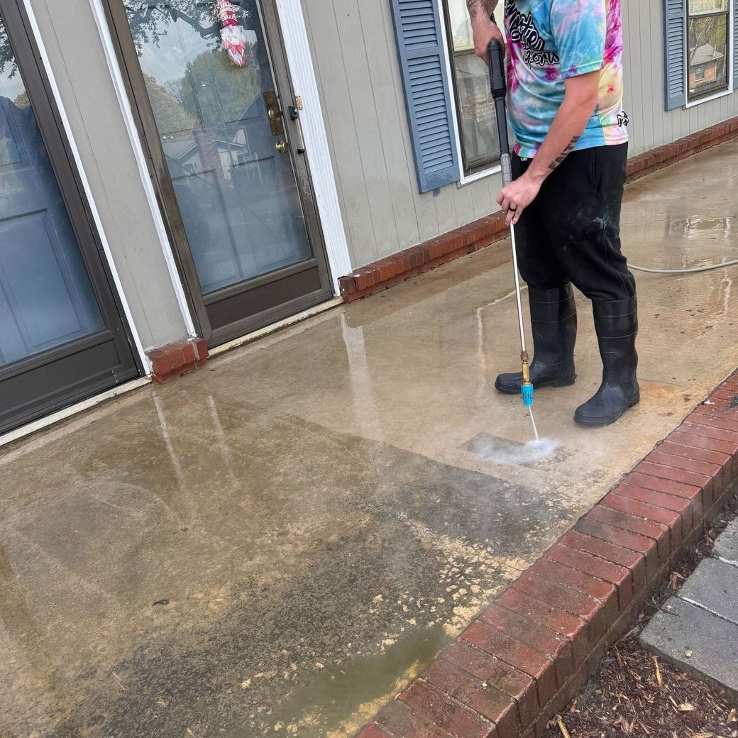 Person pressure washing a concrete porch.