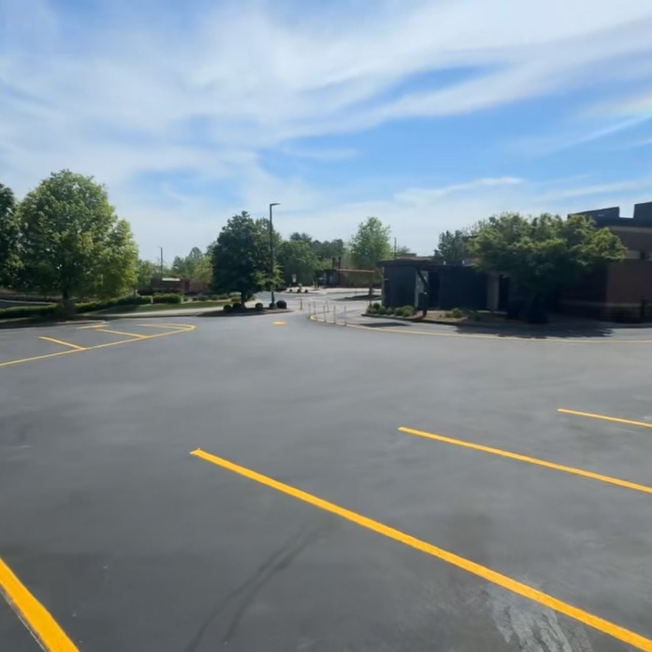 Woman in straw hat smiles, holding wine glass near a lake.