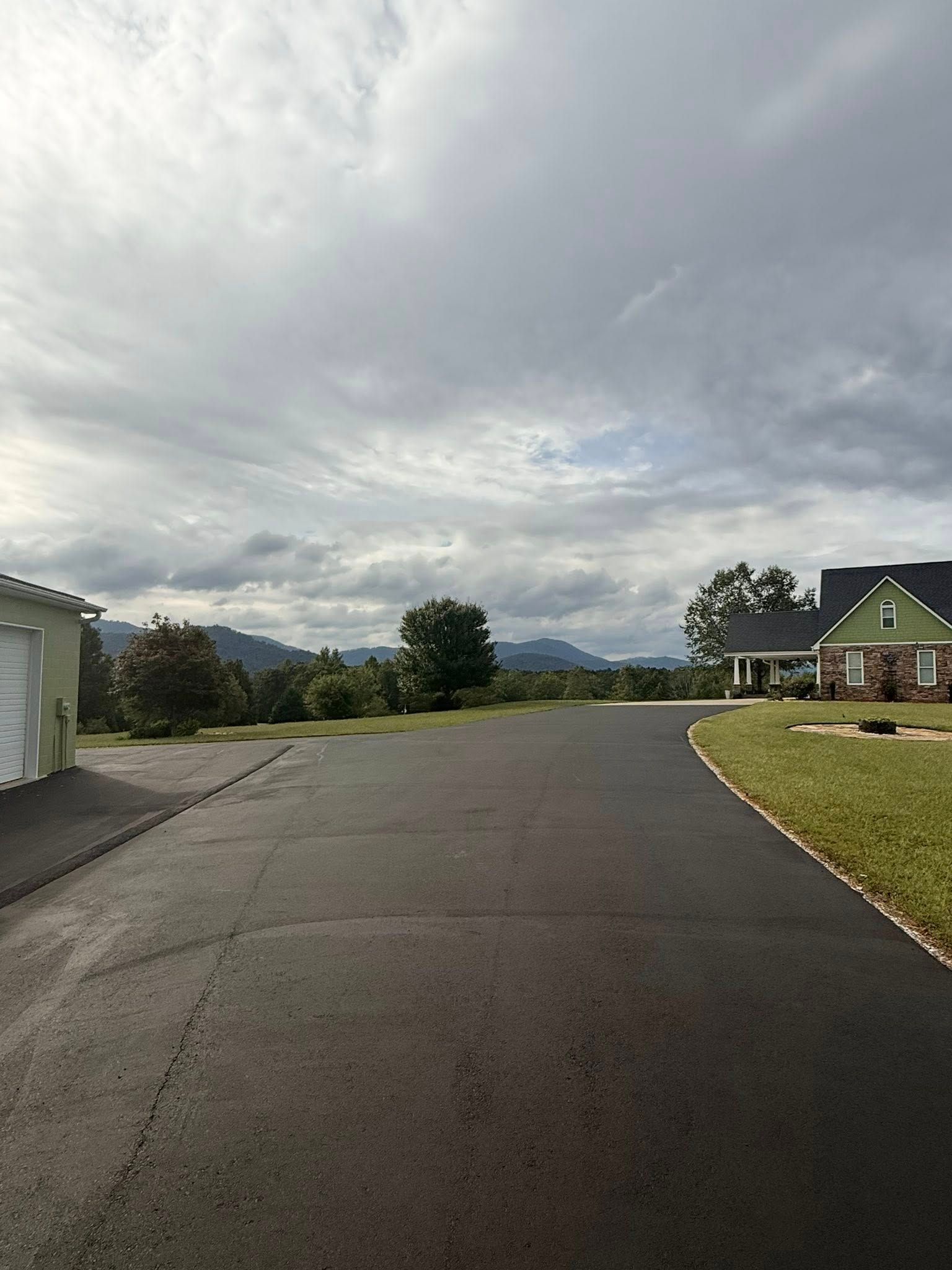 Woman in straw hat smiles, holding wine glass near a lake.