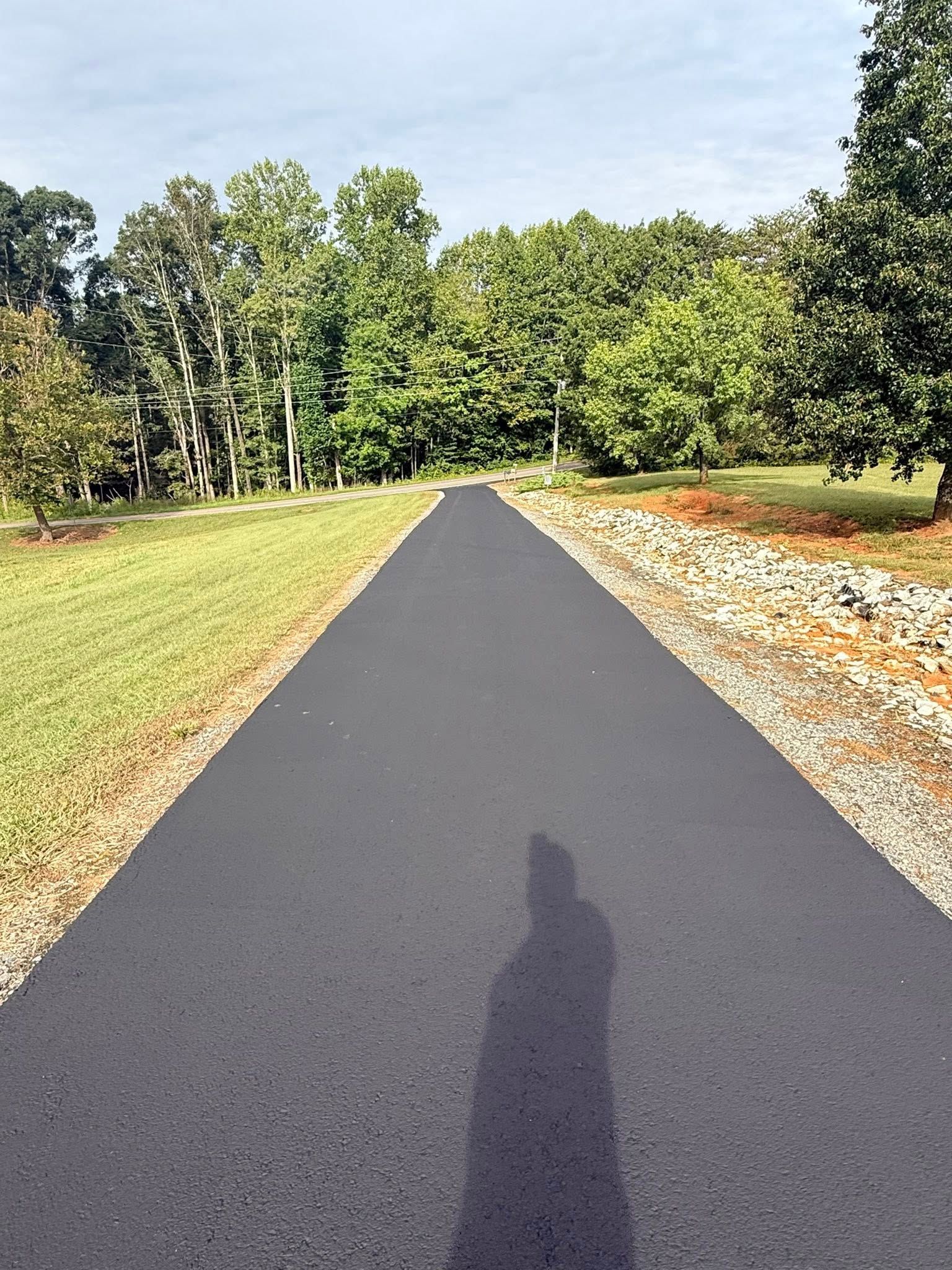 Woman in straw hat smiles, holding wine glass near a lake.