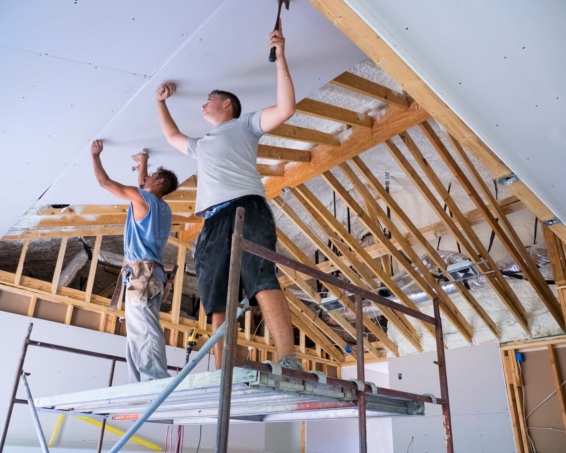 Two men are working on the ceiling of a building